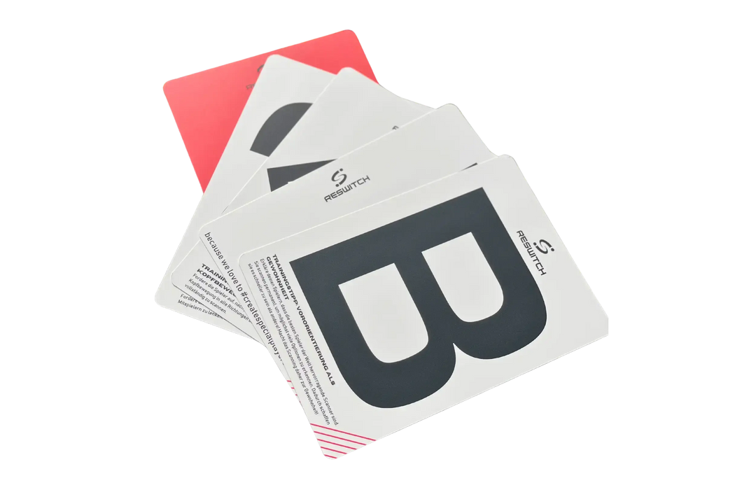 Ein aufgefächerter Stapel von matchconcept UG RESWITCH Pro-Coach Set Karten zeigt fette schwarze Buchstaben, wie B und A, auf Weiß. Auf jeder Karte ist das Reswitch-Logo abgebildet. Die oberste Karte verdeckt teilweise andere, die letzte Karte ist rot. Perfektes Trainingszubehör Fußball.