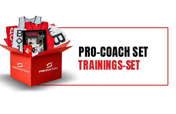 Eine rote Box mit der Aufschrift RESWITCH Pro-Coach Set von matchconcept UG enthält Fußball Trainingszubehör: Trainingsleibchen Set, Hütchen, Karten und eine Trillerpfeife. Neben der Schachtel steht der Text "PRO-COACH SET TRAININGS-SET".